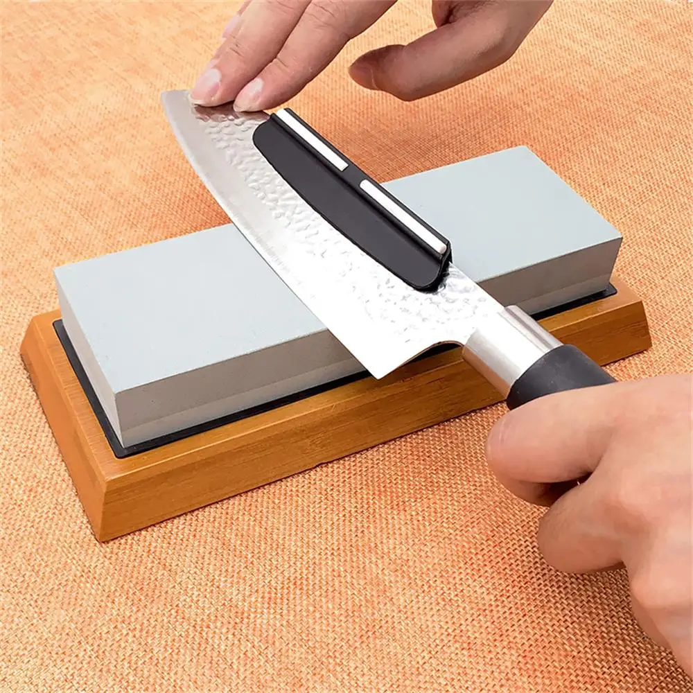 Guide d'angle en polymère clipsé sur une lame de couteau posée sur une pierre à aiguiser