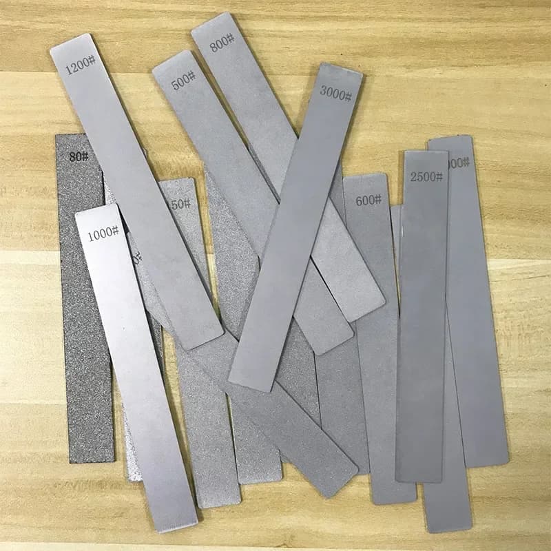 Plaques diamantées d'affûtage de plusieurs grains posées sur une planche en bois